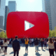 Gros bouton YouTube rouge dans une place urbaine animée